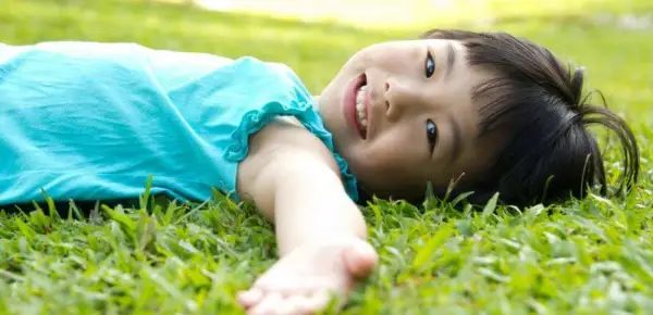 kid doing body scan in grass - Teaching Essential Mindfulness Practices and Skills body scan kids 